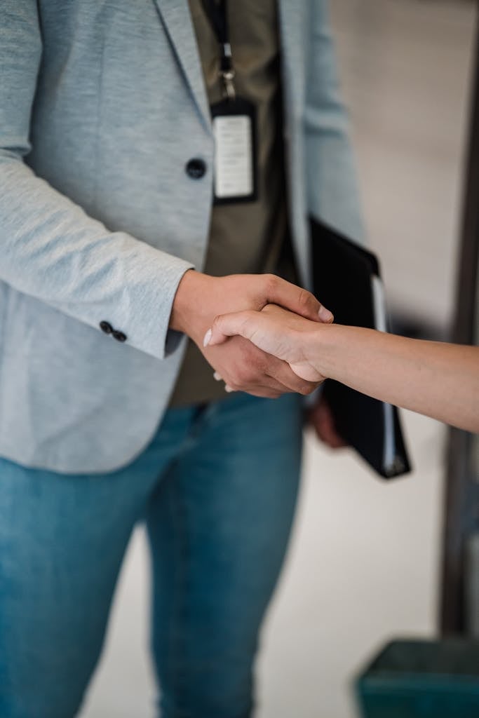 Close-up of two professionals shaking hands in a business meeting setting.